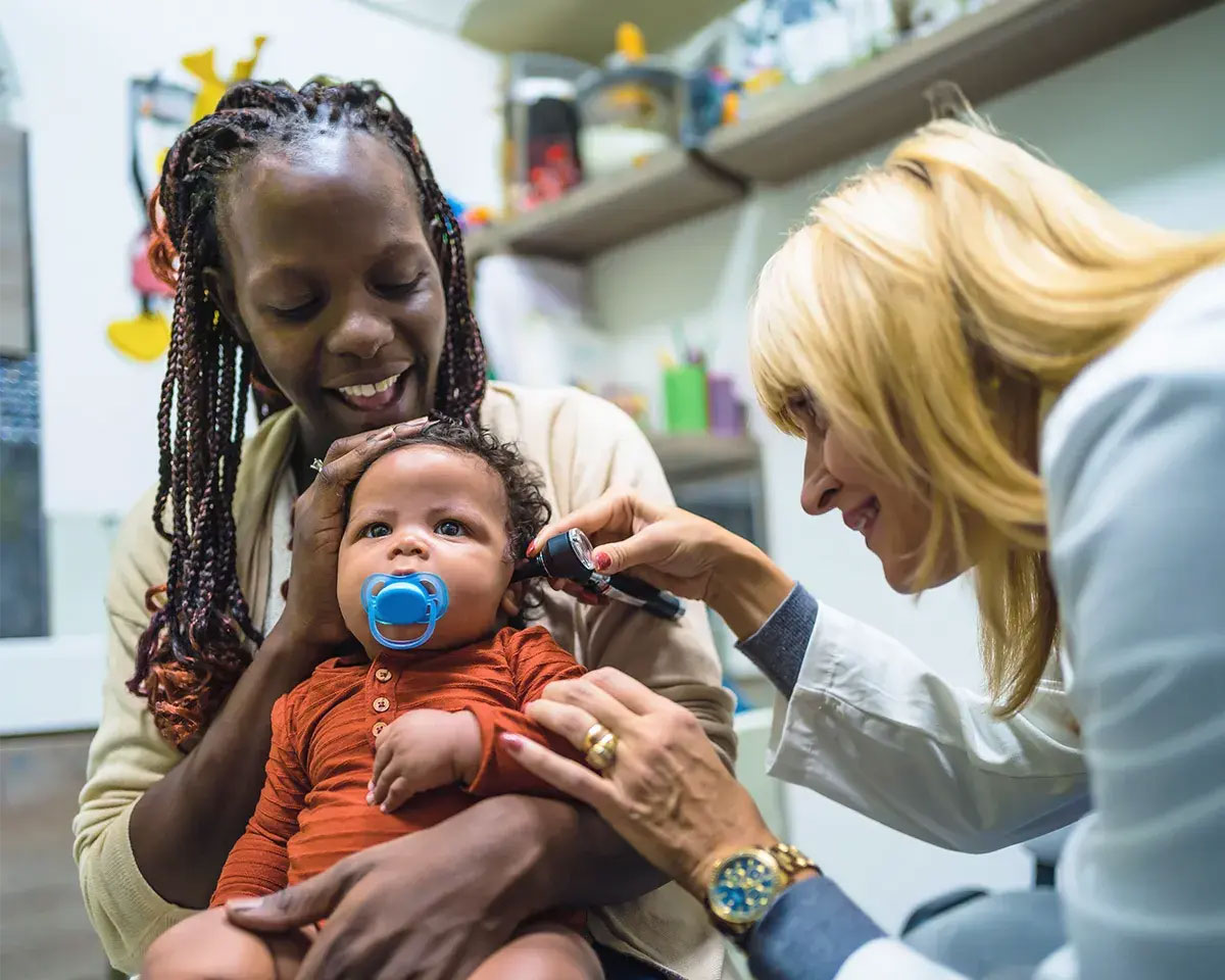 Mom holding baby while doctor looks in her ear