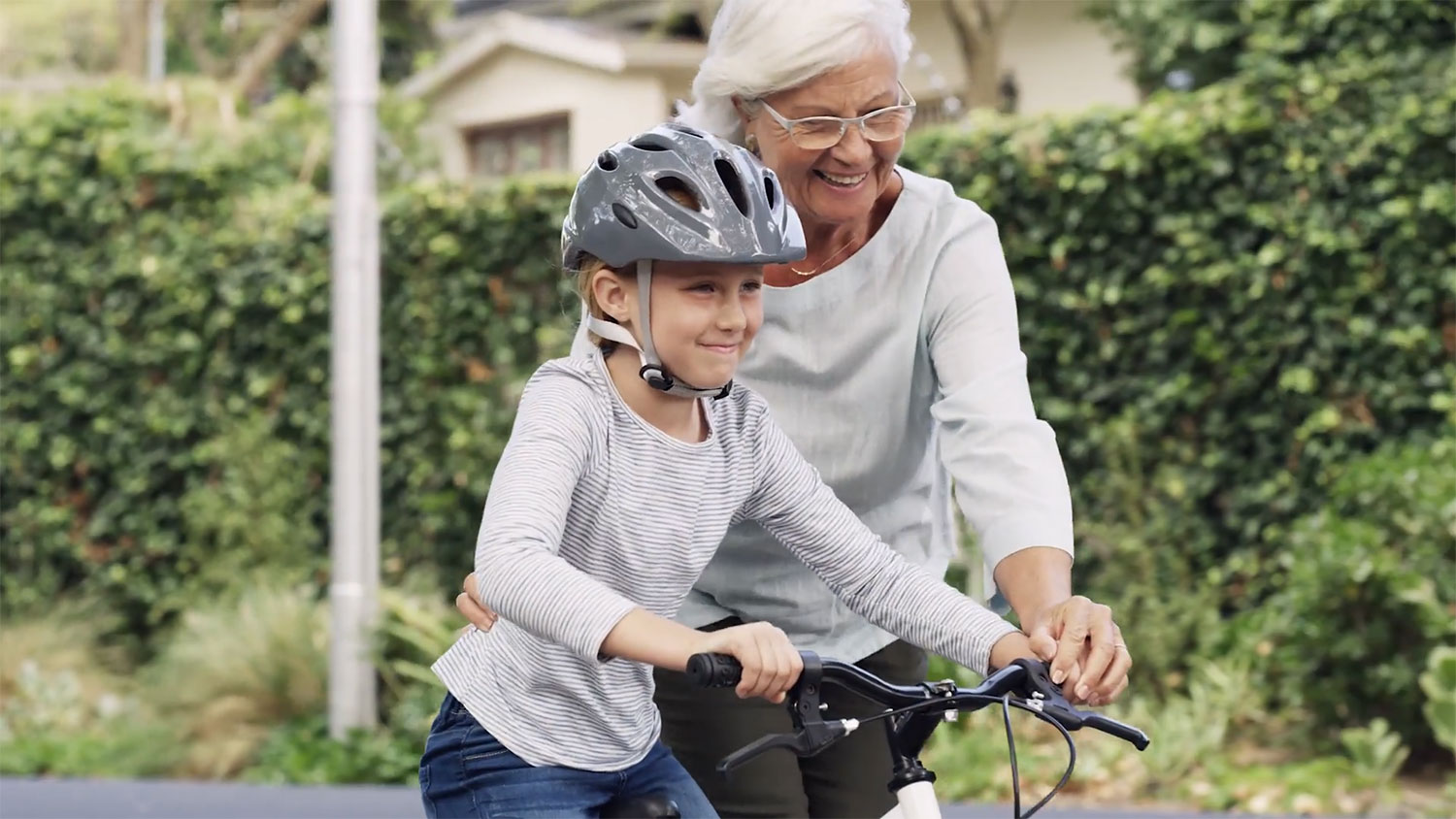 Grandma helping grandchild ride a bike
