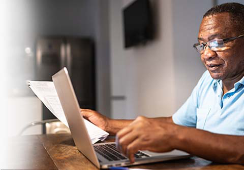 Man using a laptop and looking at papers