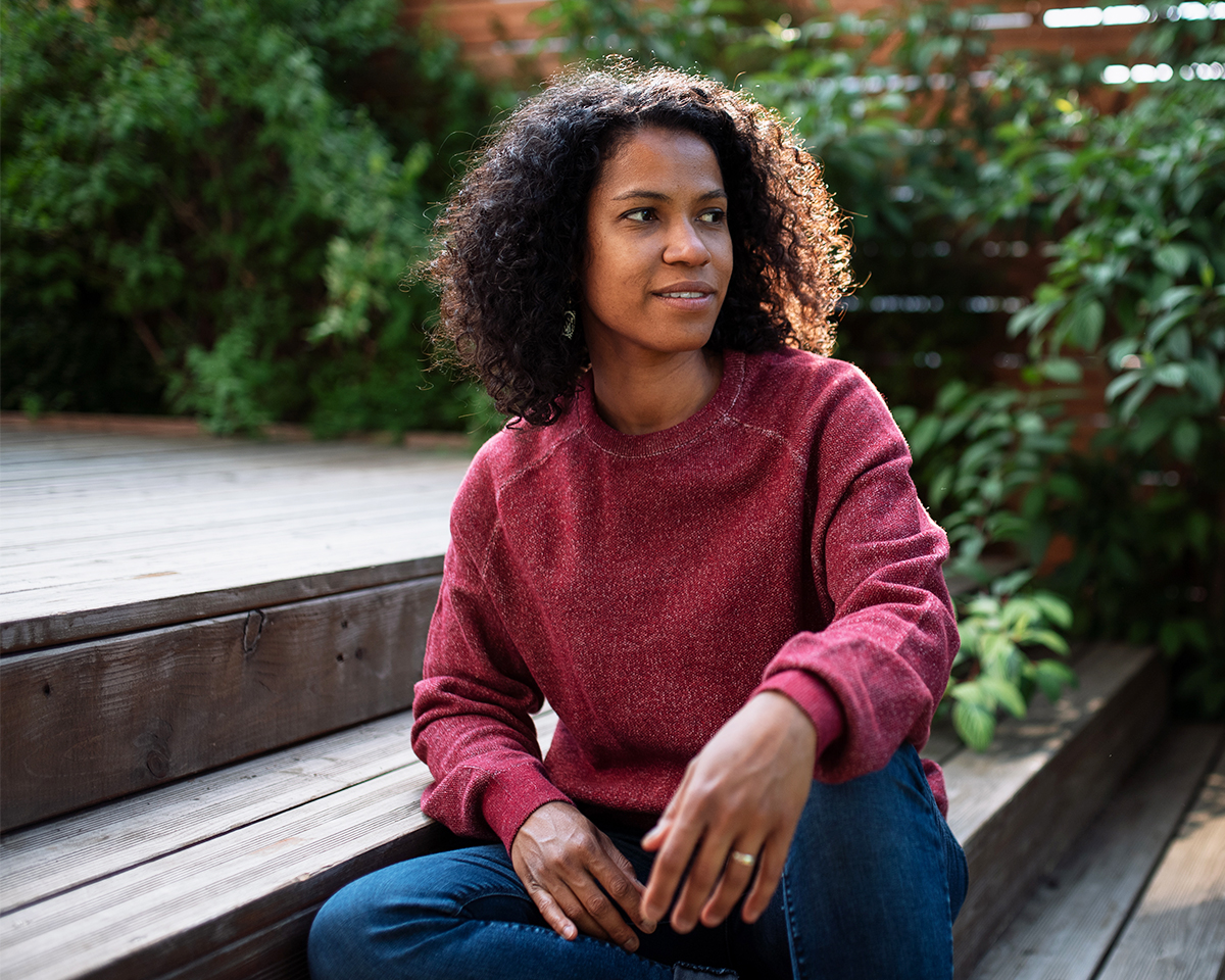Smiling Black woman sitting on the steps of an outdoor garden
