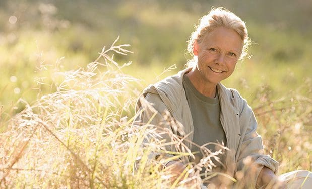 Portrait of an older smiling White woman sitting on a field