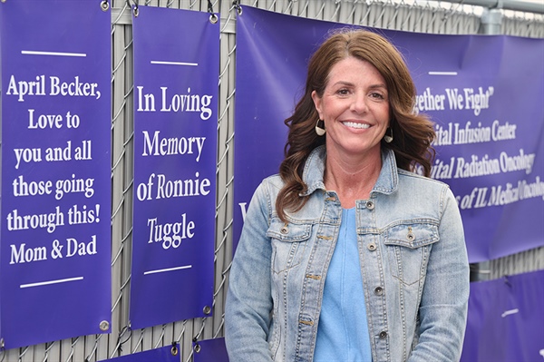 A smiling woman standing next to a poster