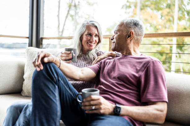 couple looking at each other on couch smiling with coffee in their hand