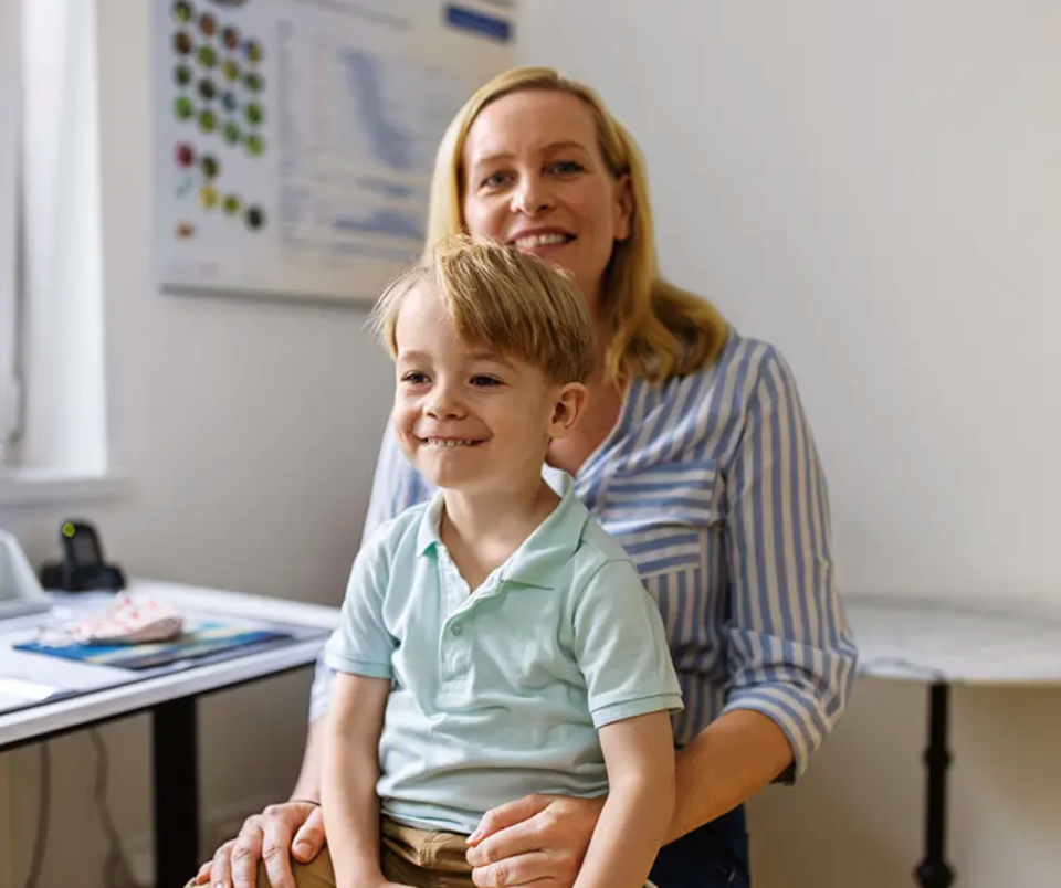 Mother with her son on her lap, both smiling and looking forward