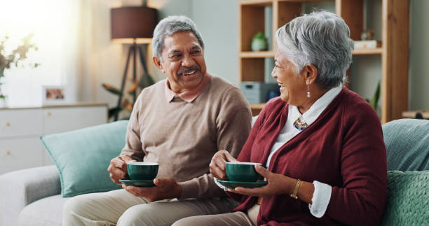 man and woman on couch drinking coffee and smiling at each other