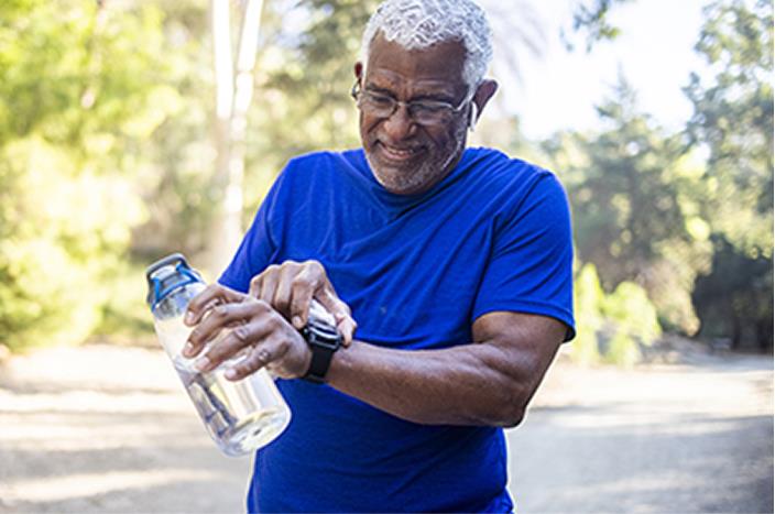 Man exercising holding a water bottle and adjusting his smart watch