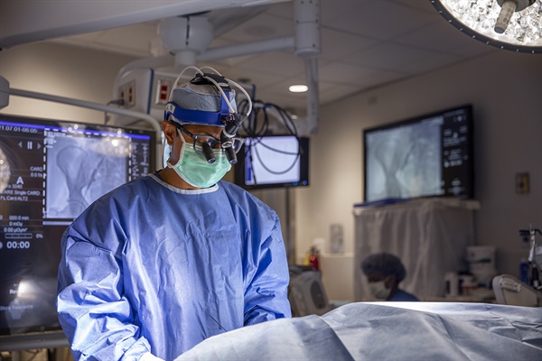 Half body shot of surgeon in Christian hospital hybrid room standing over a table.
