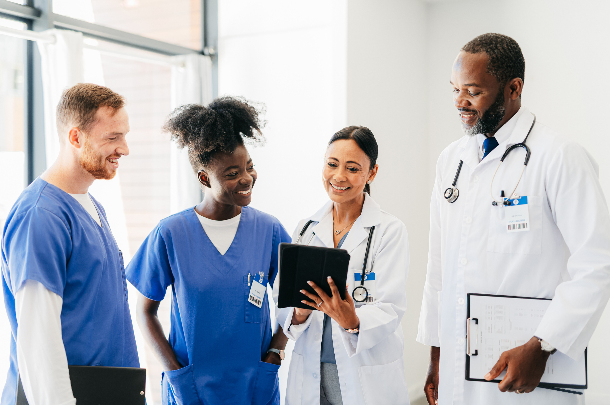 Four providers standing together in a clinical setting two wearing lab coats two wearing scrubs