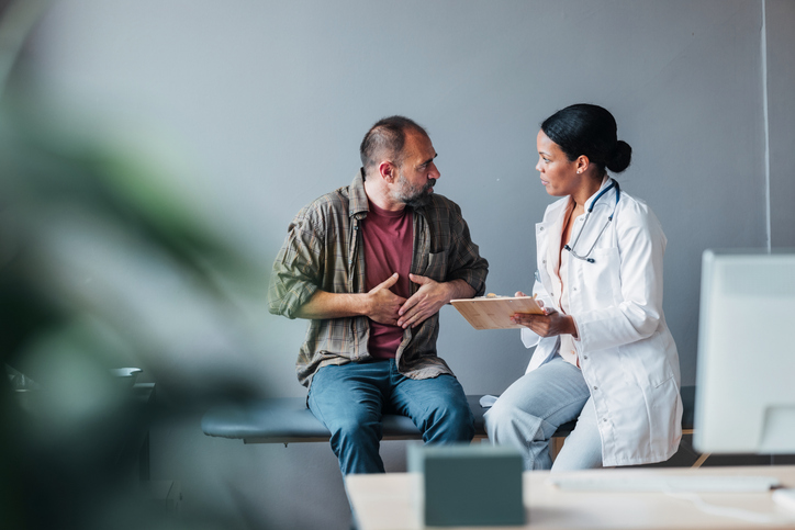 Man pressing on his abdomen talking with physician