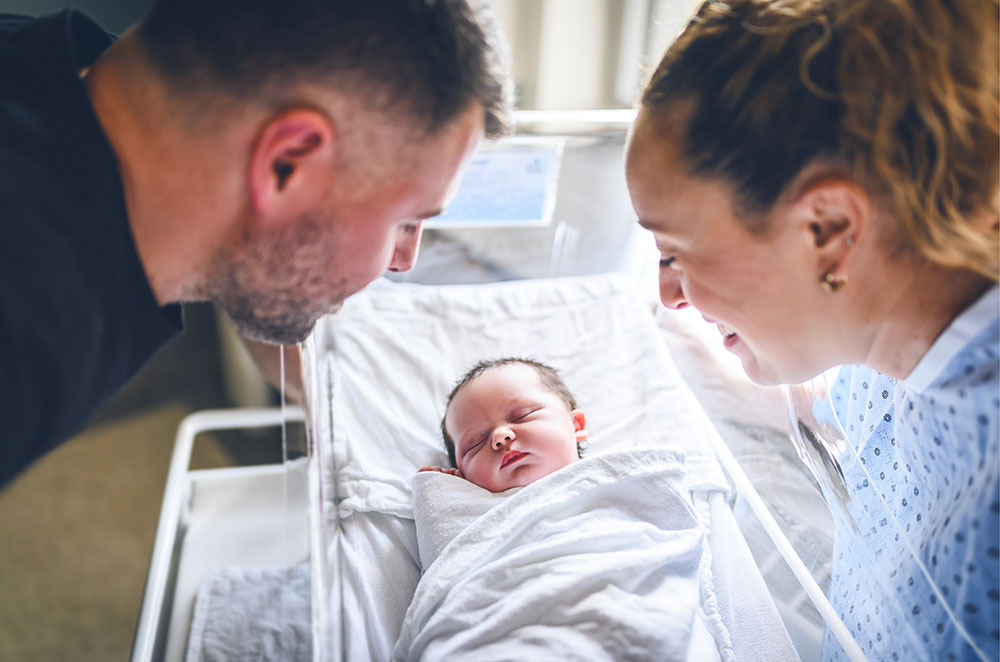 A young couple looking at a newborn baby