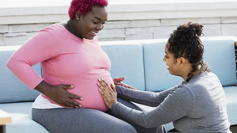 pregnant woman is admired by another woman