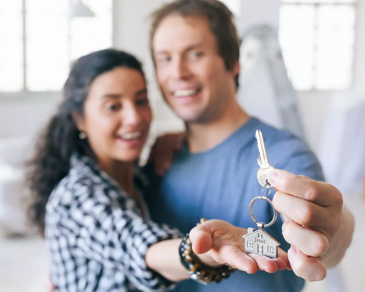 two people holding a key to their own home