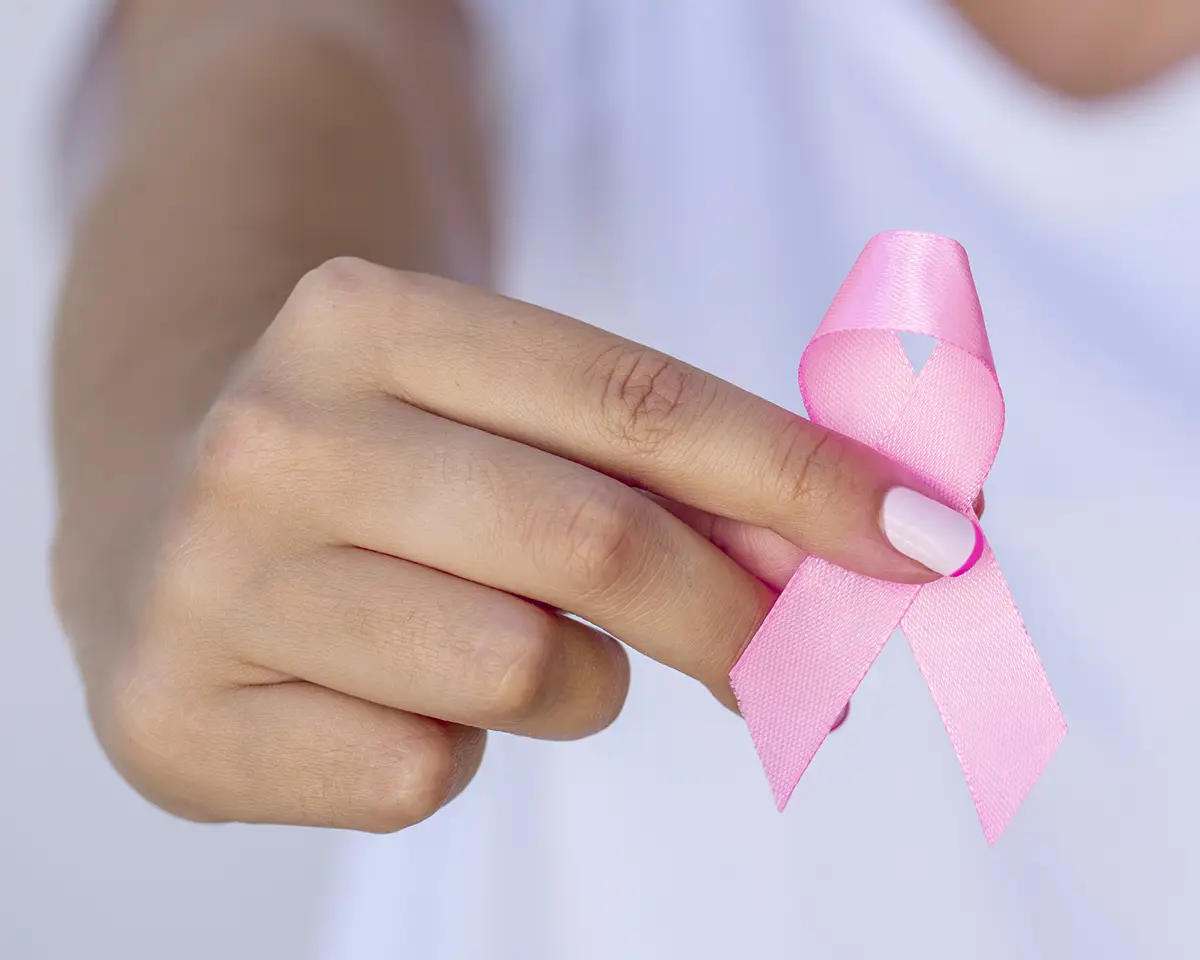 Woman's hand holding a breast cancer awareness pink ribbon