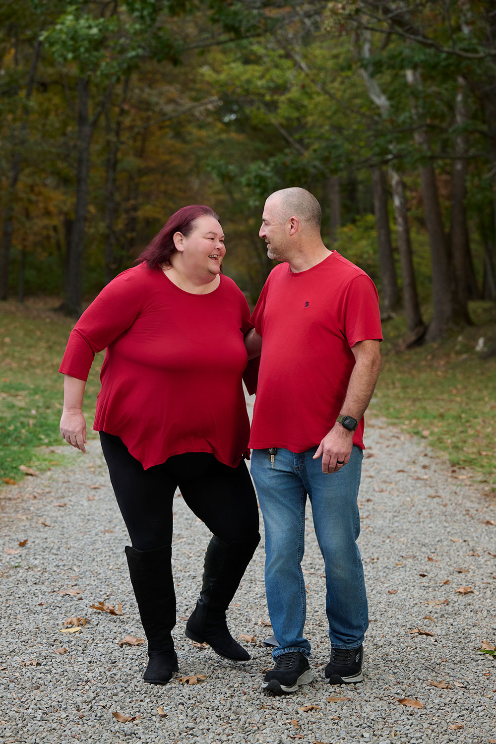 Patients Bruce and Andrea standing on a trail in a forest area and smiling at each other