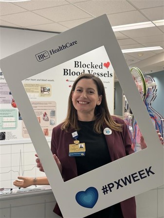 Abby Betlach holding a BJC HealthCare paper frame that over the top half of body saying #PXWEEK on bottom