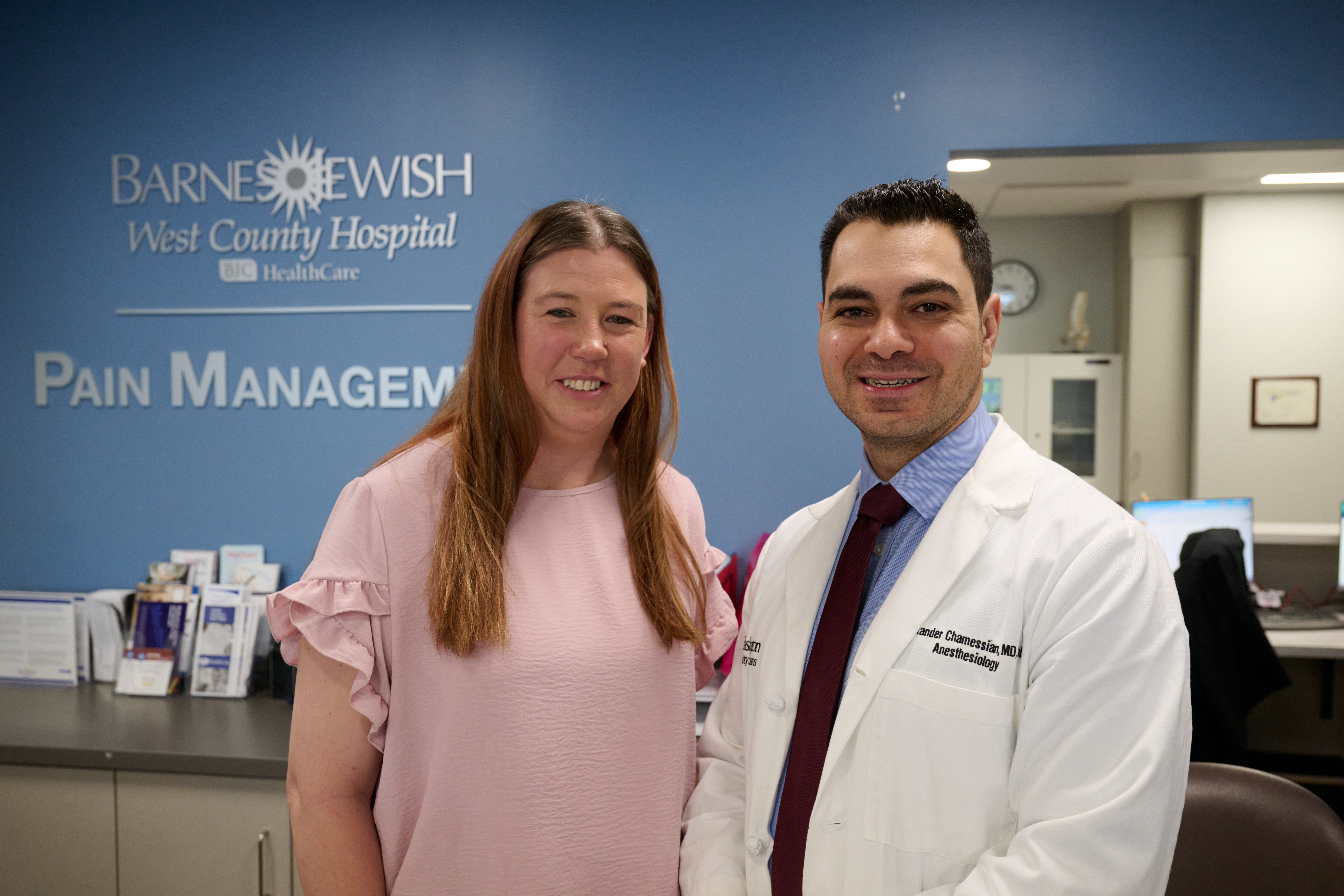 Half body shots of patient Jodi Evans (left) in pink frilly t-shirt and Dr. Alexander Chamessian in a white coat, both by a clinic front desk