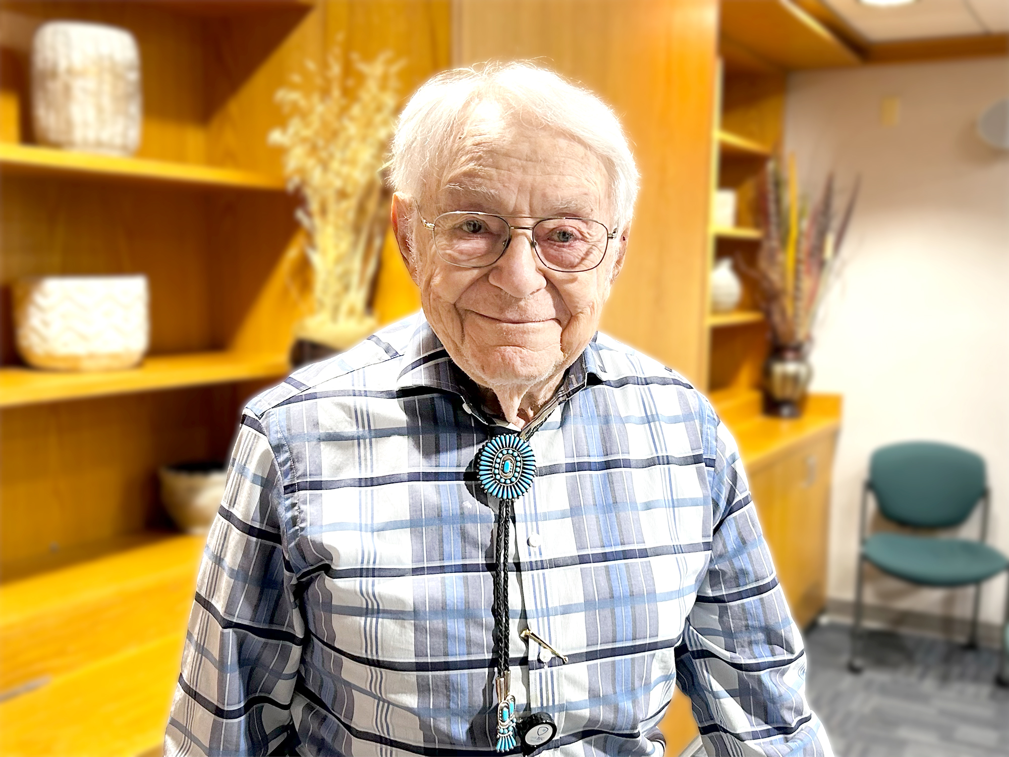 Dr. Oliver half body shot, wearing glasses, blue checkered button up and necklace