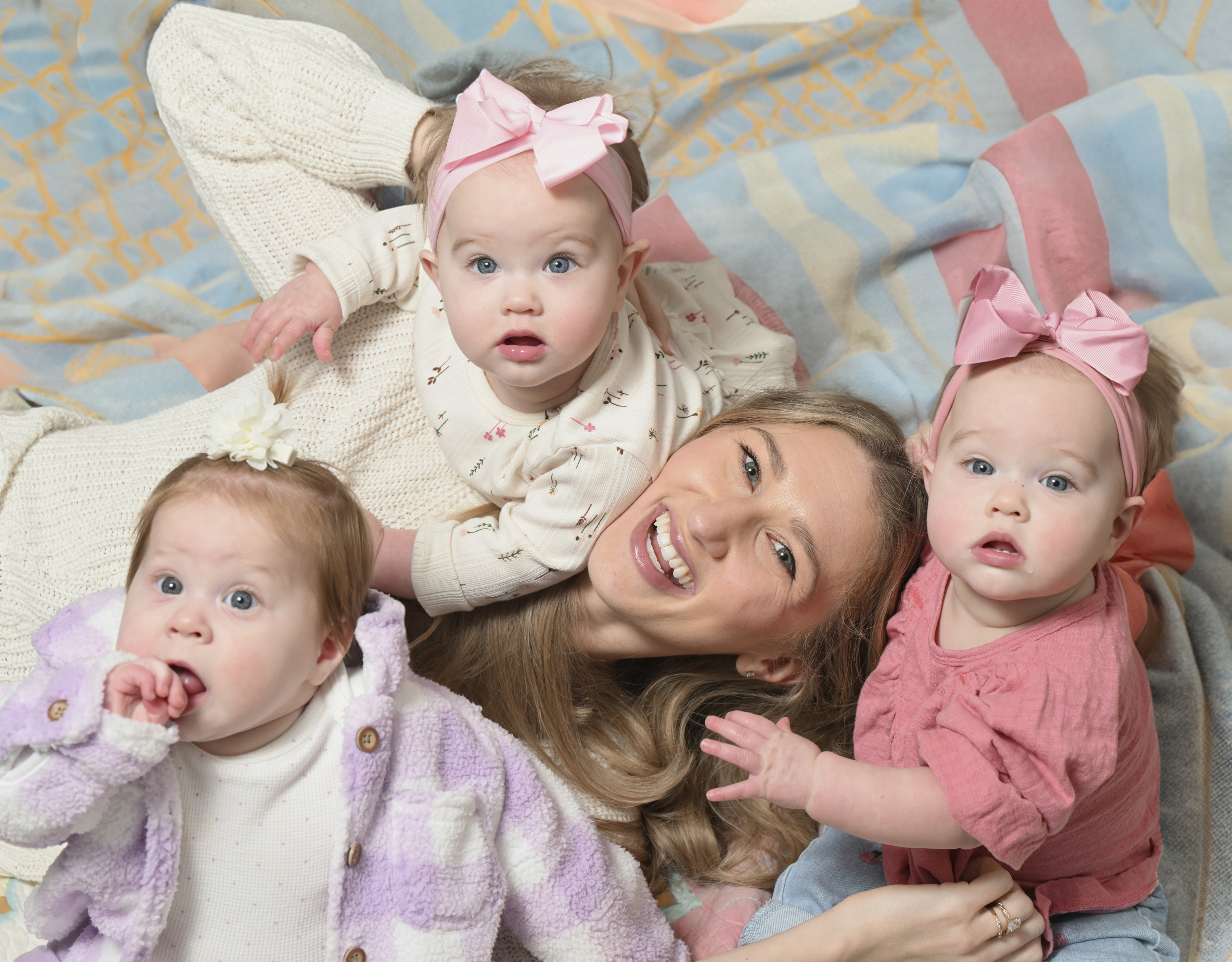 Marissa Chrissmer (center) lays down with daughters Amelia (purple shirt), Harper (pink shirt), and Charlotte (white shirt)