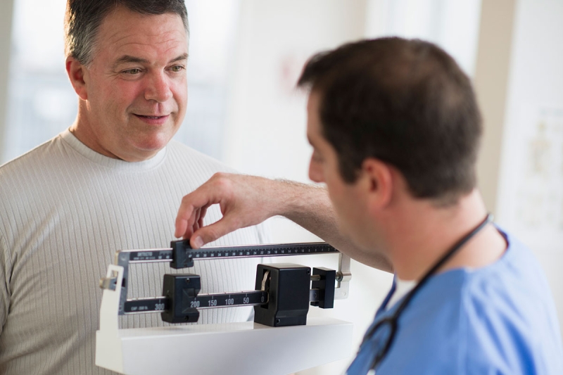 Doctor weighing a man at the doctor's office