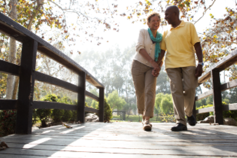 Man and woman holding hands and walking across a bridge