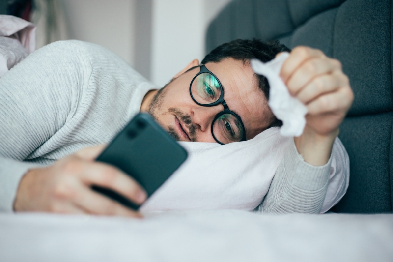 Person sick in bed on their phone