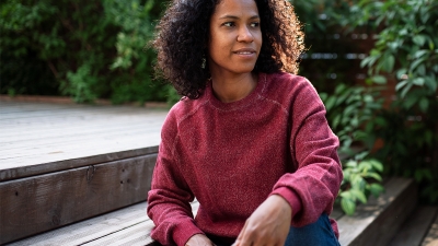 Smiling Black woman sitting on the steps of an outdoor garden
